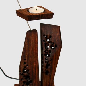 Peut inclure: Un bougeoir en bois avec un design g&eacute;om&eacute;trique. Le bougeoir a un petit porte-bougie rond sur le dessus et une base rectangulaire plus grande. Le bois est brun fonc&eacute; et a un grain naturel.