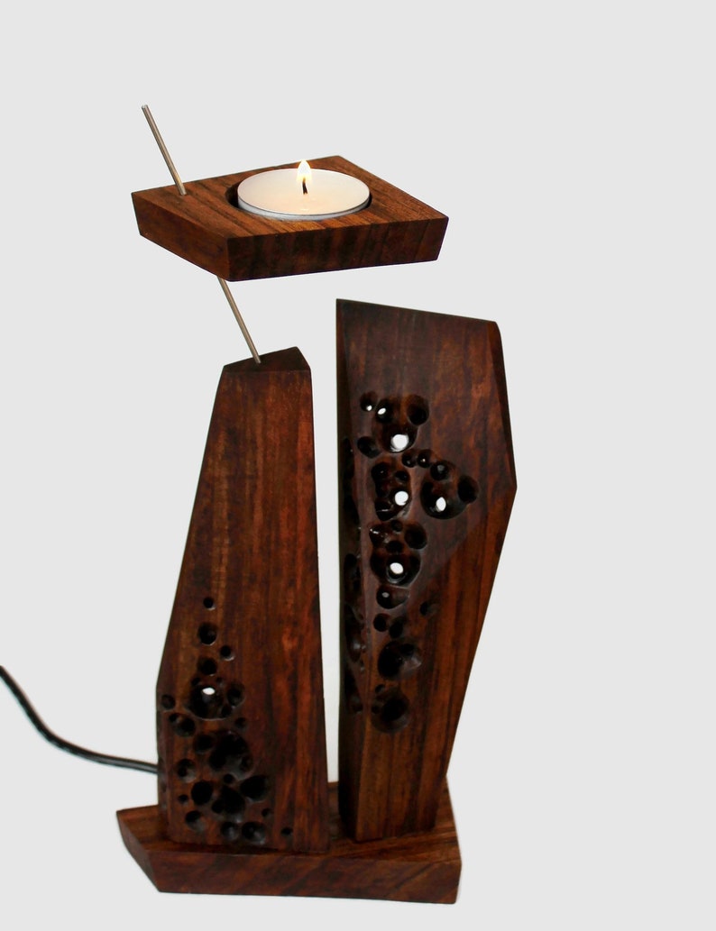 Peut inclure: Un bougeoir en bois avec un design g&eacute;om&eacute;trique. Le bougeoir a un petit porte-bougie rond sur le dessus et une base rectangulaire plus grande. Le bois est brun fonc&eacute; et a un grain naturel.