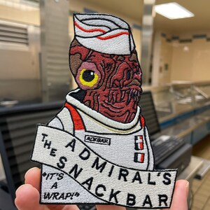 May include: Embroidered patch featuring a grotesque alien figure in a white uniform with red accents and a chef's hat. The patch reads "THE ADMIRAL'S SNACKBAR" and "IT'S A WRAP!" in black text.