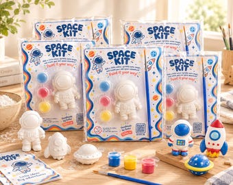 May include: Space Kit craft sets in clear plastic packaging, each containing a white ceramic astronaut figurine, three small paint pots in blue, red, and yellow, and a paintbrush. The packaging features space-themed graphics and text.