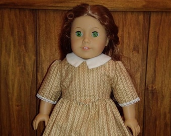 May include: A doll wearing a brown and white striped dress with a white collar and lace trim. The doll has green eyes and red hair.