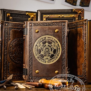 K&ouml;nnte beinhalten: Eine Sammlung handgefertigter, ledergebundener B&uuml;cher mit aufwendigen gepr&auml;gten Designs. Die braunen Einb&auml;nde sind mit goldenen Akzenten versehen, darunter dekorative Nieten und kreisf&ouml;rmige Symbole. Die B&uuml;cher werden mit Werkzeugen pr&auml;sentiert, was auf Handarbeit hindeutet.