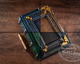 May include: A rectangular leather journal with a gradient blue and green cover, featuring ornate embossed borders and brass-toned metal corner accents. A gold-toned fountain pen rests beside the journal, which displays the text Handmade By aLexLibris.