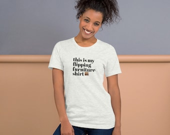 Könnte beinhalten: Ein hellgraues T-Shirt mit schwarzem Text, der "This is my flipping furniture shirt" lautet, und einer kleinen braunen Grafik eines Möbelstücks.