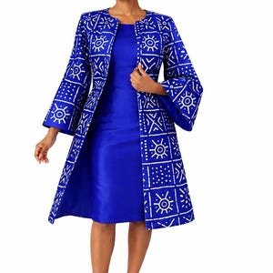Könnte beinhalten: Ein kobaltblaues Kleid und eine passende Jacke mit Muster. Die Jacke hat ein weißes geometrisches Design. Das Outfit wird durch blaue Absätze ergänzt. Das Kleid hat einen runden Ausschnitt und reicht bis zu den Knien.