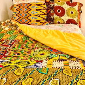 May include: A yellow, green, and brown patterned quilt with a yellow, green, and brown patterned pillow on top. The quilt is made of different fabrics with various patterns.