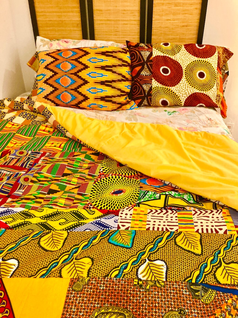 May include: A yellow, green, and brown patterned quilt with a yellow, green, and brown patterned pillow on top. The quilt is made of different fabrics with various patterns.
