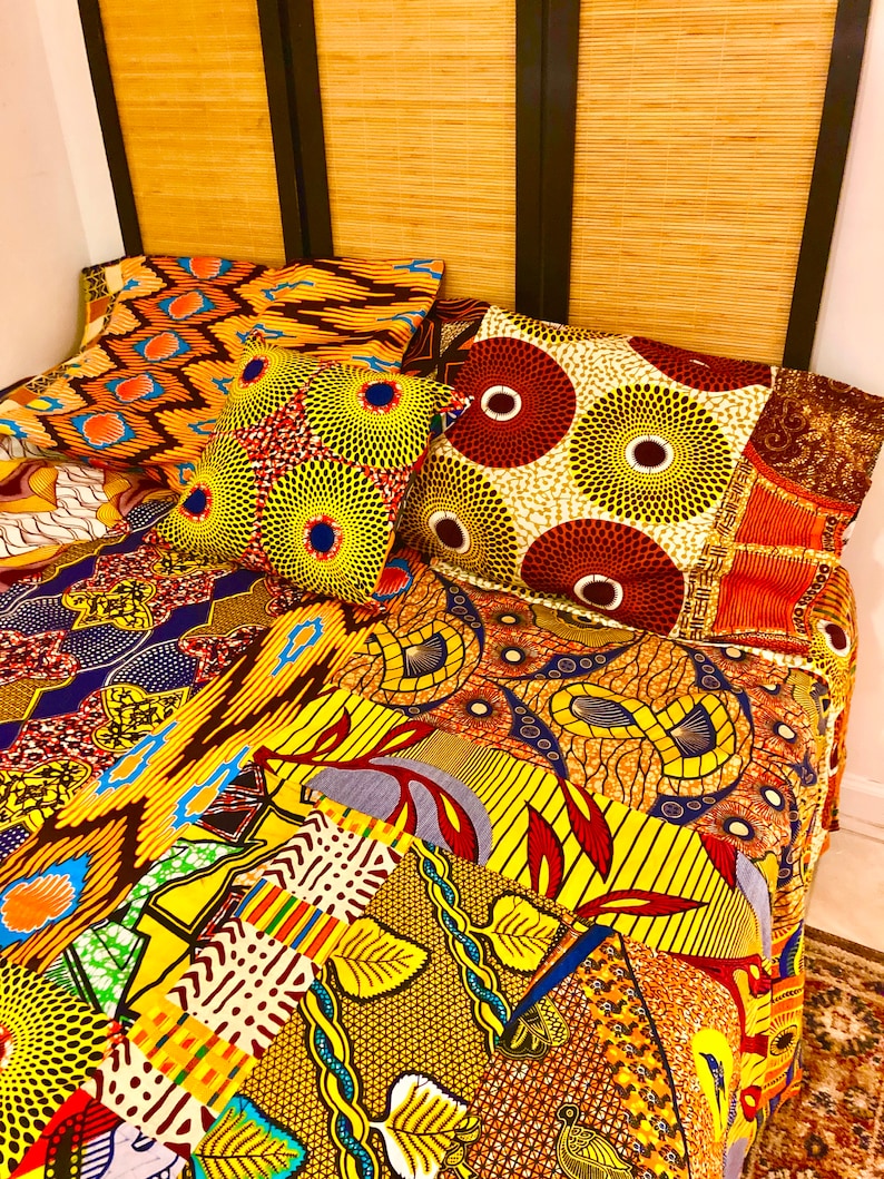 May include: A colorful patchwork quilt with a variety of African print fabrics in yellow, orange, red, blue, and brown. The quilt is made up of different patterns and designs, including geometric shapes, floral motifs, and animal prints.