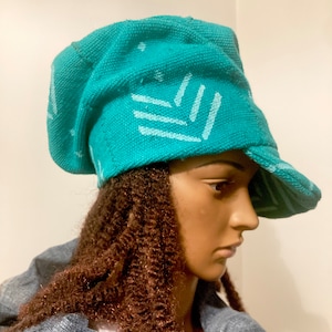 May include: A turquoise blue hat with a white geometric pattern. The hat has a wide brim and is made of a soft, textured fabric.
