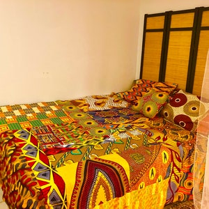 May include: A bed with a colorful patchwork quilt featuring yellow, red, green, and brown patterns. The bed has a headboard made of a wooden screen with black accents. There are several patterned pillows on the bed.