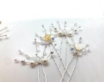 May include: Set of five silver hair pins with pearl and crystal accents. Each pin features a different charm, including a starfish, a seashell, and a pearl.