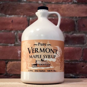 May include: A white gallon jug of pure Vermont maple syrup with a brown label featuring a red barn and trees. The label reads "Pure Vermont Maple Syrup" and "3.79 L One Gallon 128 Fl. Oz."