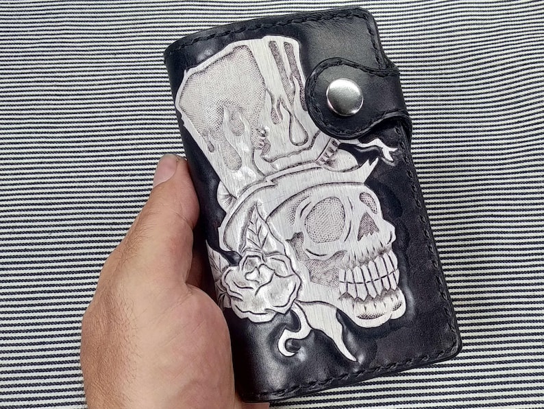 May include: Black leather wallet with a tooled design of a skull wearing a top hat and a rose.