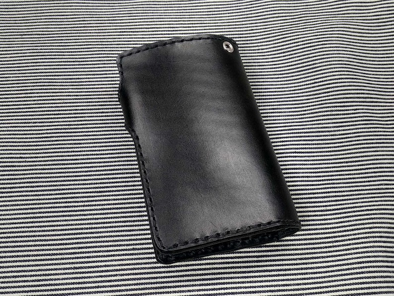 May include: A black leather wallet with a stitched edge and a silver snap closure.