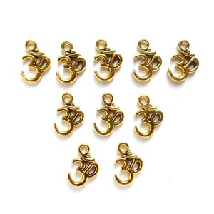 May include: Ten gold-colored metal charms featuring the Om symbol. The charms are small and have a loop at the top for attaching to jewelry or other crafts.