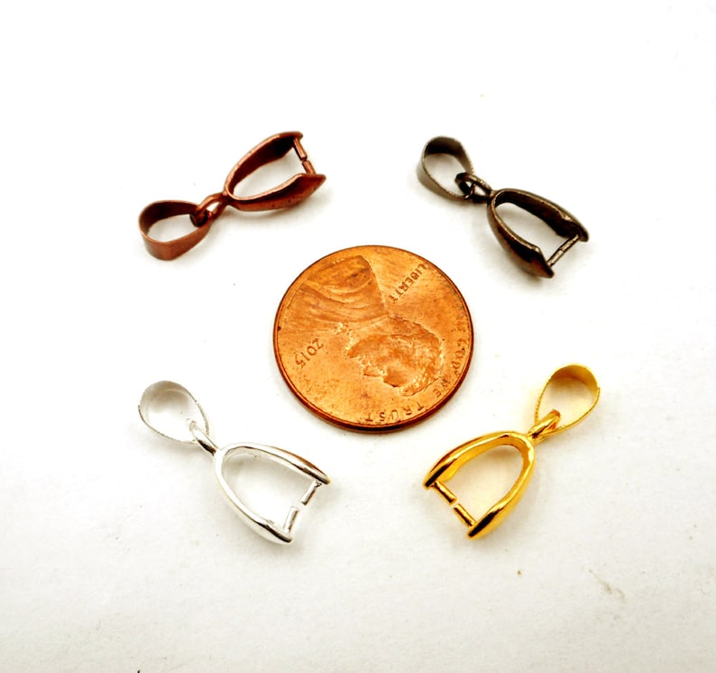 May include: Four pendant bails in different finishes: silver, gold, copper, and black. The bails are shown next to a US penny for size comparison.