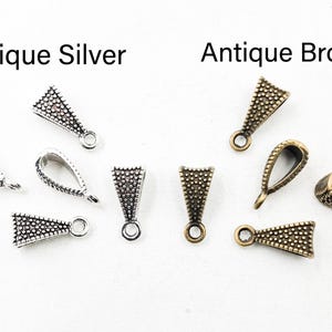 May include: A collection of triangular pendant bails featuring a textured, beaded surface. The set includes four pieces in an antique silver finish and four pieces in an antique bronze finish, each with a small circular loop for attachment.