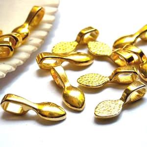 Peut inclure: Un groupe de bélières de pendentif en métal doré avec une forme de larme. Les bélières ont une surface texturée et une boucle en haut pour attacher un pendentif.