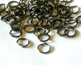May include: A pile of small, gold-toned jump rings. The rings are made of metal and are about 1/2 inch in diameter.