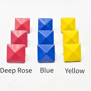 May include: Three sets of square-shaped stud earrings in deep rose, blue, and yellow. Each earring has a pyramid design. The colors are labeled below the earrings. The earrings are on a white background.