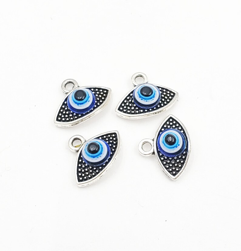 May include: Four silver charm pendants with blue evil eye designs. Each pendant has a loop at the top for attaching to a necklace or bracelet.