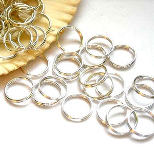 May include: A pile of silver jump rings, a type of jewelry finding used for connecting chains, cords, and other jewelry components.