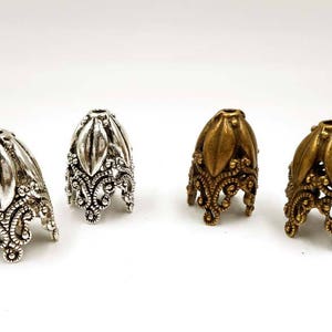 May include: Four ornate metal bead caps, two silver and two gold, with a decorative floral design.