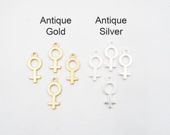 Puede incluir: Encantos antiguos de oro y plata en forma de símbolo femenino.