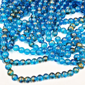 May include: A strand of blue glass beads with gold flecks. The beads are round and have a shiny finish.