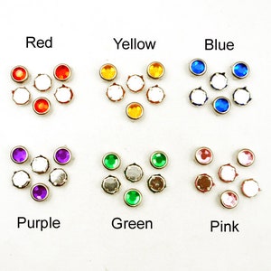 May include: Assortment of colorful rhinestones in red, yellow, blue, purple, green, and pink. Each color is arranged in a small cluster of seven rhinestones.