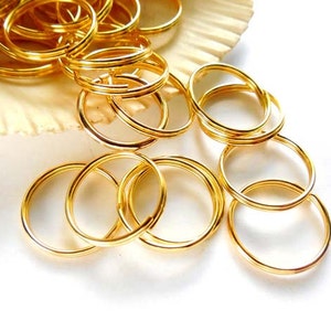 May include: A pile of gold-colored metal key rings. The key rings are round and have a smooth finish.