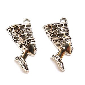May include: Two silver charm pendants in the shape of an Egyptian queen's head wearing a crown. The charms are detailed with intricate designs and have a slightly aged finish.
