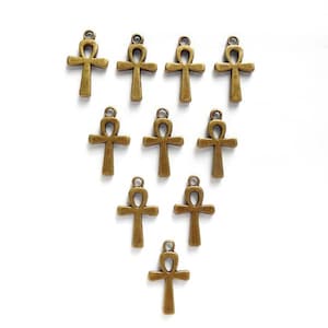May include: Ten bronze Ankh charms arranged in a triangular pattern on a white background.