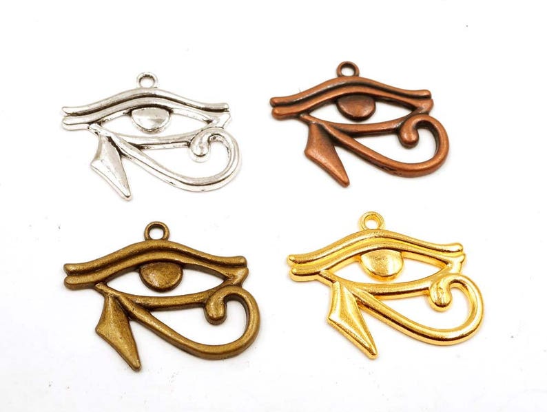 May include: Four silver, gold, and bronze charms in the shape of the Eye of Horus, an ancient Egyptian symbol of protection and good health.