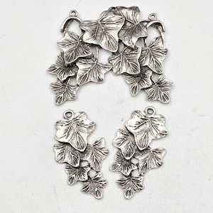 May include: Silver tone metal charms in the shape of ivy leaves. The charms are in a cluster of leaves and are perfect for jewelry making or crafting.