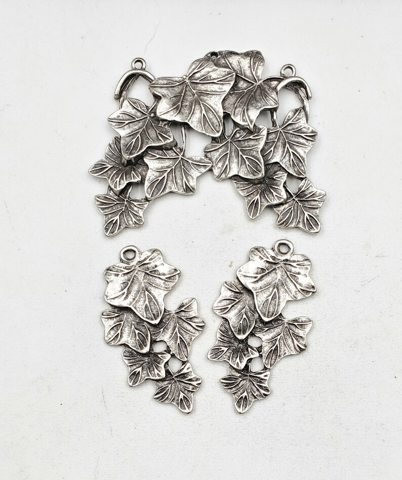 May include: Silver tone metal charms in the shape of ivy leaves. The charms are in a cluster of leaves and are perfect for jewelry making or crafting.