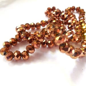 May include: A strand of copper-colored faceted glass beads. The beads are round and have a shiny, metallic finish.