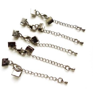 May include: Six silver-toned chain extenders with square clasps. Each extender has a small, decorative square charm at each end.