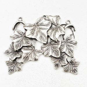 May include: Silver-toned metal charm featuring a cluster of ivy leaves. The leaves are detailed and realistic, with a textured surface.