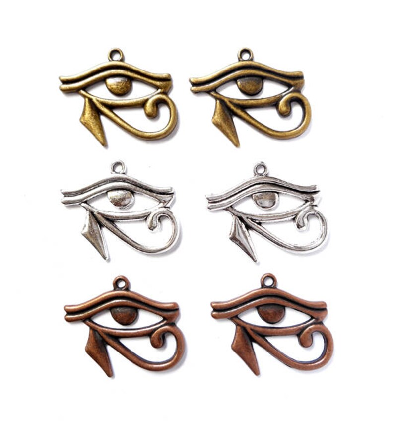 May include: Six metal charms in the shape of the Eye of Horus. Two are gold, two are silver, and two are copper.