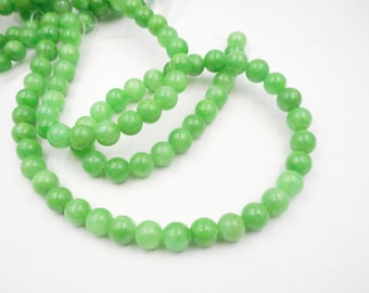 May include: A strand of light green jade beads. The beads are round and smooth, and they are strung on a clear string.