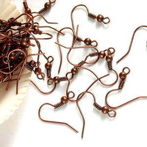May include: A pile of copper-colored earring hooks with a small ball at the end of each hook.