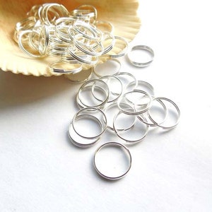 May include: A pile of silver jump rings, a type of jewelry finding, are spilling out of a seashell. The rings are small and round, and they are perfect for making jewelry.