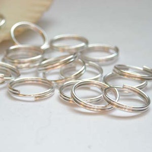 May include: A pile of silver jump rings, a type of jewelry finding used for connecting chains, cords, and other jewelry components.