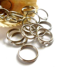 Könnte beinhalten: Ein Haufen silberner Schlüsselringe, einige liegen übereinander. Die Schlüsselringe sind alle gleich groß und gleich geformt.