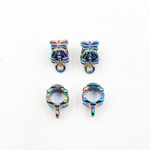 May include: Four iridescent metal jewelry findings. Two are bell-shaped with a loop at the bottom, and two are open-ended with a loop. The findings have a rainbow finish, reflecting colors like blue, green, and purple.