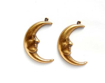 May include: Two gold-tone crescent moon charms with a face sculpted into the moon. The charms have a hole at the top for attaching to jewelry.