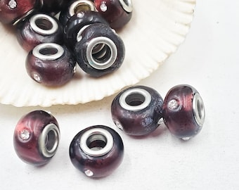 May include: A collection of dark red and silver beads with a crystal accent. The beads have a metallic silver core and are displayed in a white seashell. The beads are a deep burgundy color.