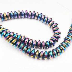 May include: A strand of iridescent hematite beads, each bead is a flat disc with a rainbow sheen. The beads are strung together to form a necklace or bracelet.