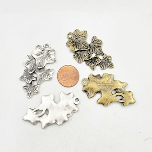 May include: Four metal leaf charms in silver and gold tones. The charms are in the shape of ivy leaves and are perfect for jewelry making or crafting.